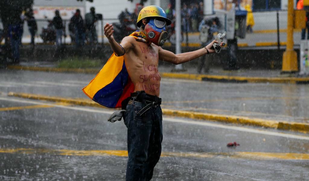 
En man demonstrerar mot regeringen i regnet i Caracas, Venezuela. Foto: 
Ariana Cubillos/AP/TT                                            