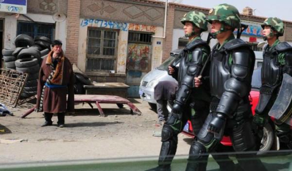 



Skyltar på kinesiska syns på denna bild av en tibetansk man i traditionella kläder som betraktar kinesiska paramilitärer i kravallutrustning i Guomaying på den tibetanska platån.  Foto: Frederic J. Brown/AFP/Getty Images                                                                                                                                                                                