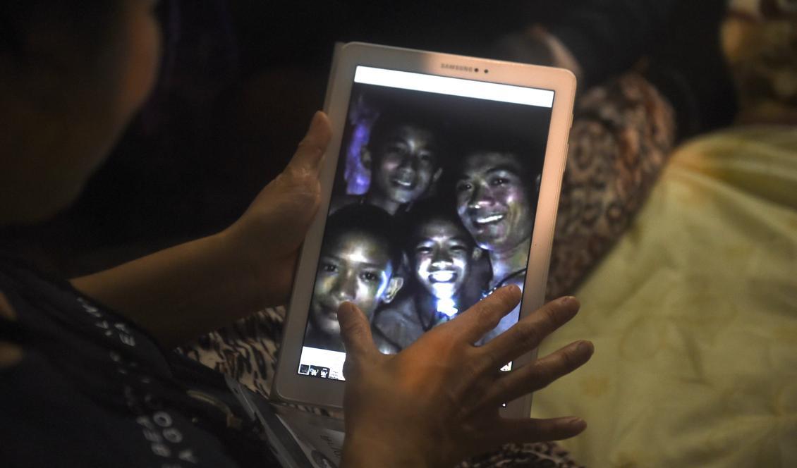 

En lycklig anhörig betraktar ett fotografi med de thailändska pojkar som suttit instängda i en grotta i nio dygn. Foto: Lillian Suwanrumpha/AFP/TT                                                                                        