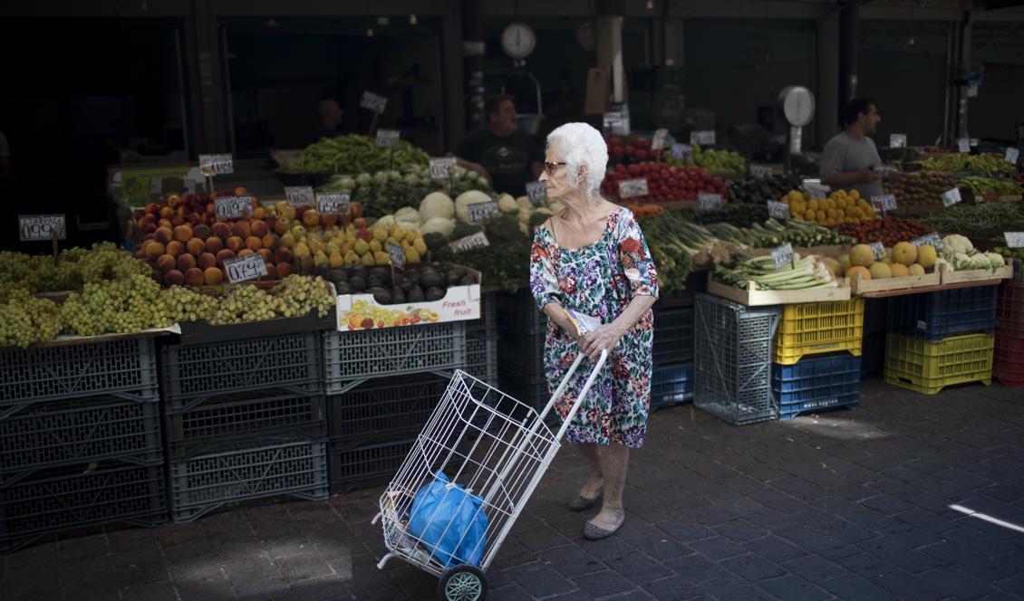 En äldre kvinna handlar frukt och grönsaker i Aten. Många grekiska pensionärer är missnöjda med de åtstramningar som har gjorts under åren av stödprogram. Foto: Petros Giannakouris/AP/TT-arkivbild