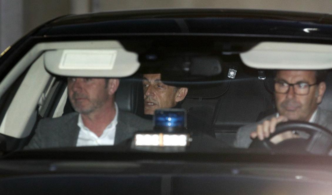 Frankrikes tidigare president Nicolas Sarkozy skymtar i baksätet i en polisbil. Bilden är från i mars i år när han förhördes på en polisstation i Nanterre utanför Paris. Foto: Francois Mori/AP/TT