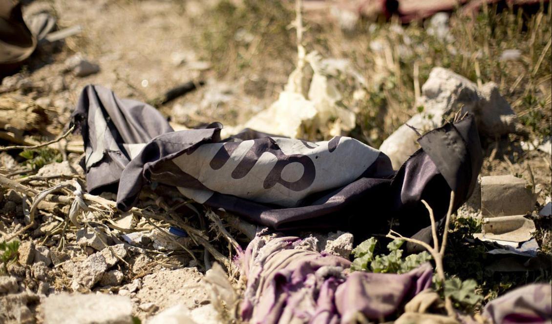 En av terrorrörelsen IS flaggor blev kvar på marken efter att IS drivits bort från sitt sista fäste al-Baghuz i Syrien. Foto: Maya Alleruzzo/AP/TT