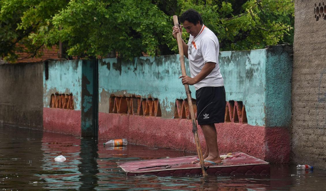 En boende i Asunción använder en madrass som tillfällig flotte. Foto: Norberto Duarte/AFP/TT