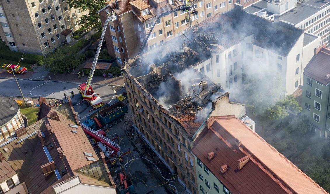 Arbetet efter branden i ett äldre flerfamiljshus i centrala Malmö fortsatte på fredagskvällen. Bit för bit lyfts takkonstruktionen ner för att brandmännen skall komma åt lättare. Foto: Johan Nilsson/TT