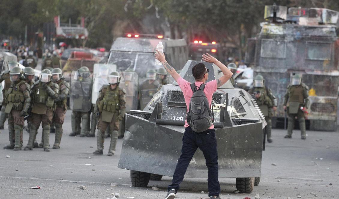 En demonstrant framför ett polisfordon under protester i Chiles huvudstad Santiago den 19 november. Foto: Esteban Felix/AP/TT