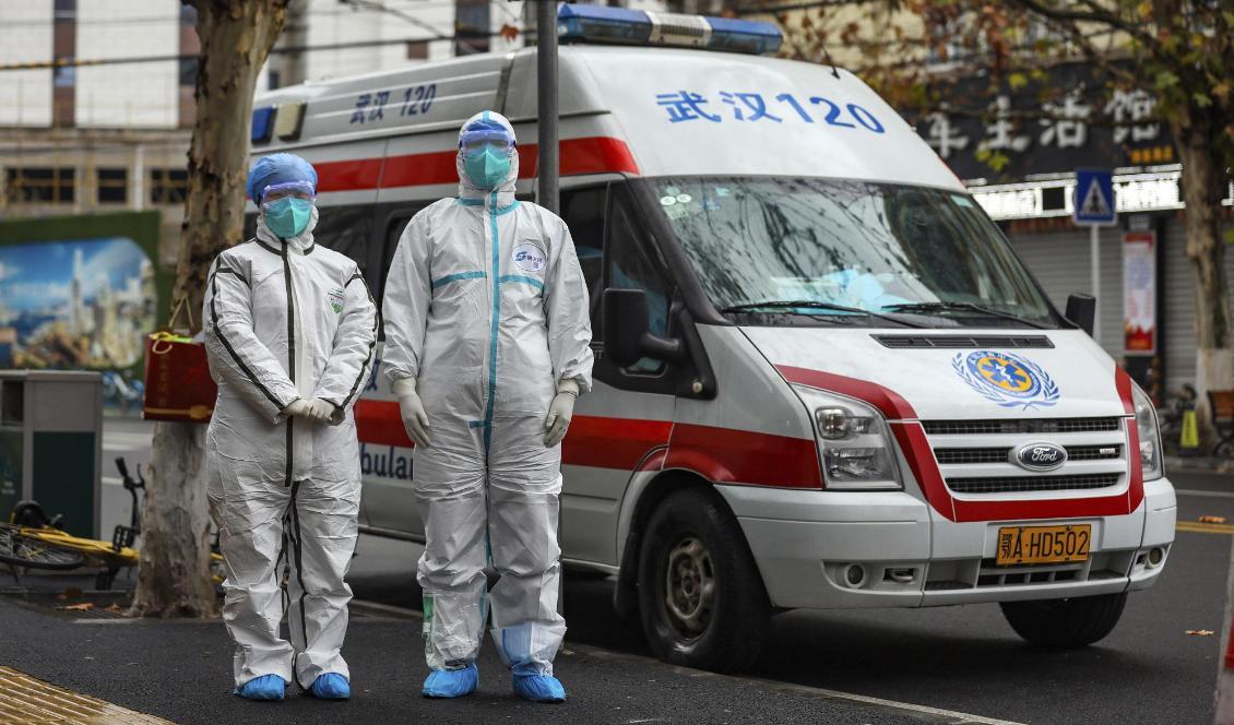 Ambulanspersonal i skyddsutrustning väntar på en patient vid ett bostadsområde i Wuhan. Foto: AP/TT