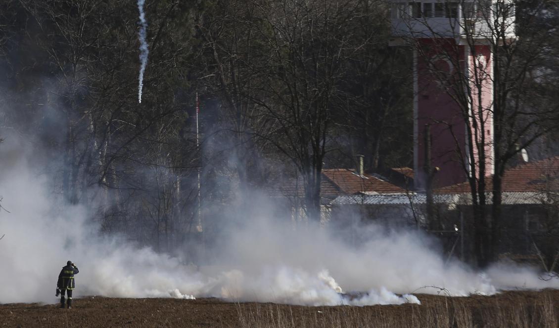 En grekisk brandman nära gränsstängslet medan tårgas används under sammandrabbningar vid gränsen mellan Grekland och Turkiet. Foto: Giannis Papanikos/AP/TT