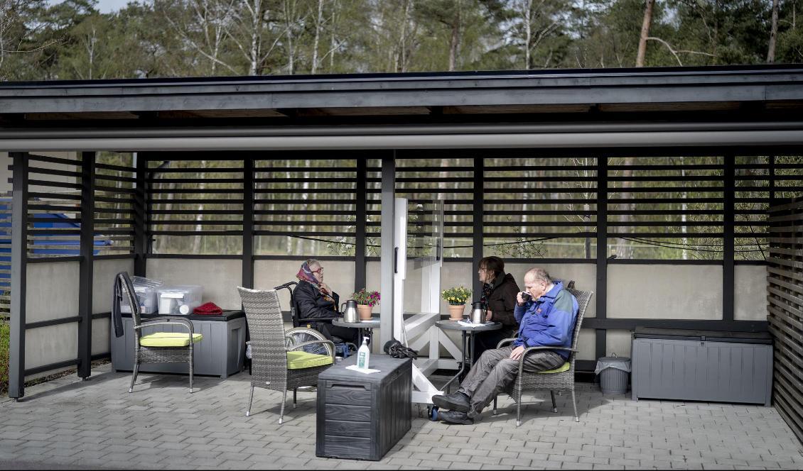 Nils Oskar Svensson och hans dotter Madeleine Westerberg besöker sin fru och mamma Siv Svensson, boende på Tallgläntan i Falkenberg. Med hjälp av plexiglasväggen kan boende på Tallgläntans äldreboende och anhöriga ses igen. Foto: Björn Larsson Rosvall/TT