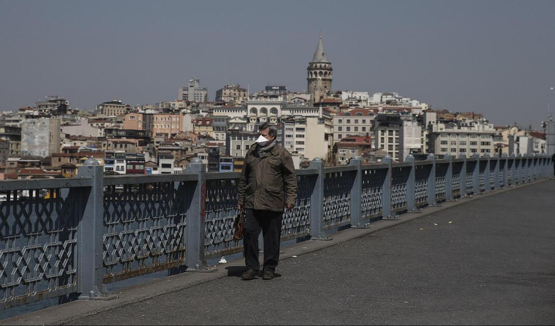 I Turkiet införs ett 48-timmars långt utegångsförbud från och med midnatt natten mot lördagen på flera håll i landet. Bland annat i mångmiljonstaden Istanbul. På bilden en man med munskydd på den berömda Galatbron i staden. Foto: Emrah Gurel/AP/TT