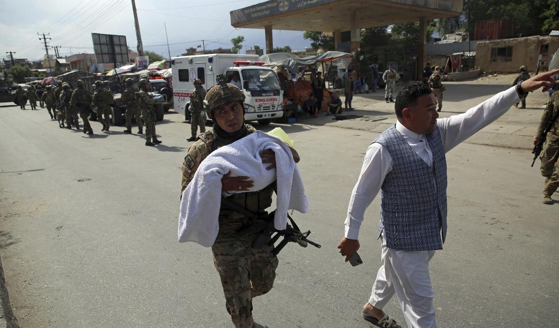 En afghansk soldat bär på ett barn efter att beväpnade män angripit en förlossningsklinik i Kabul i tisdags. Foto: Rahmat Gul/AP/TT