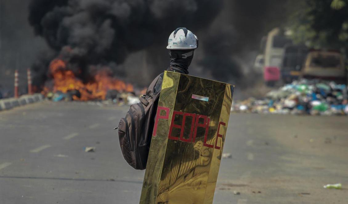 En demonstrant framför brinnande bildäck i Myanmars största stad Rangoon i förra veckan. Arkivbild. Foto: AP/TT