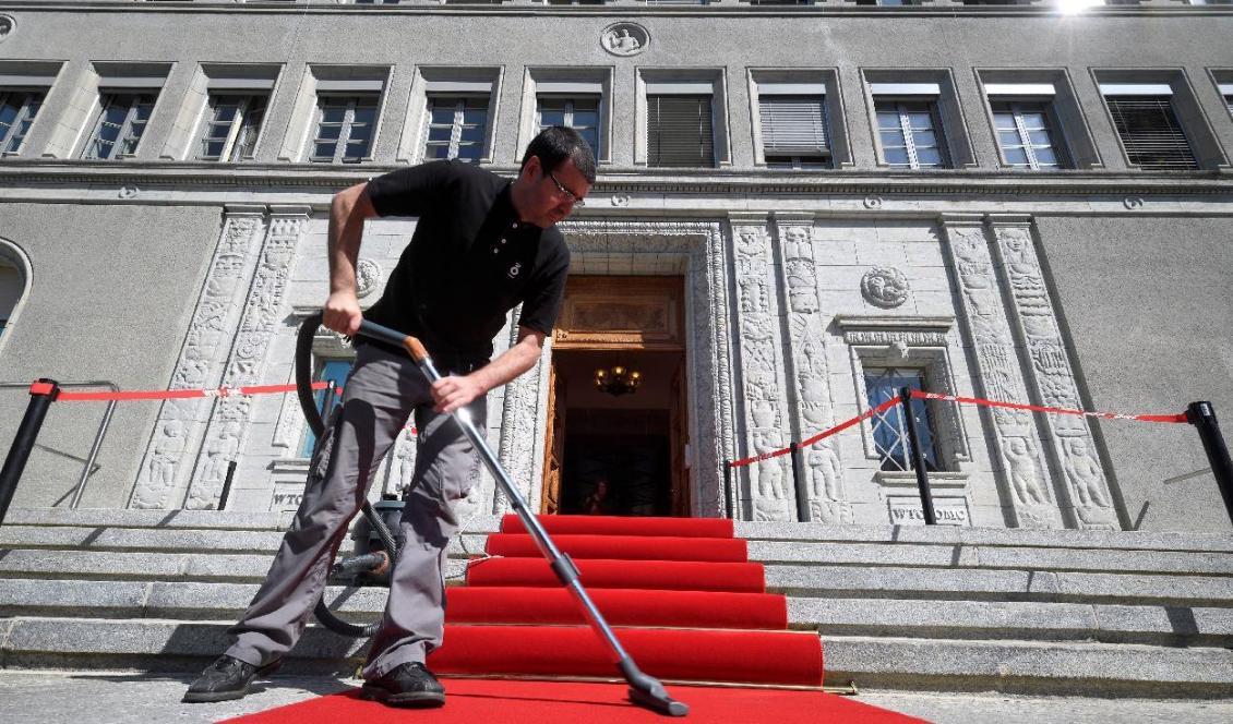 

En man dammsuger den röda mattan i samband med en välkomstceremoni vid Världshandelsorganisationens (WTO) högkvarter i Genève. Foto: Fabrice Coffrini/AFP via Getty Images                                             