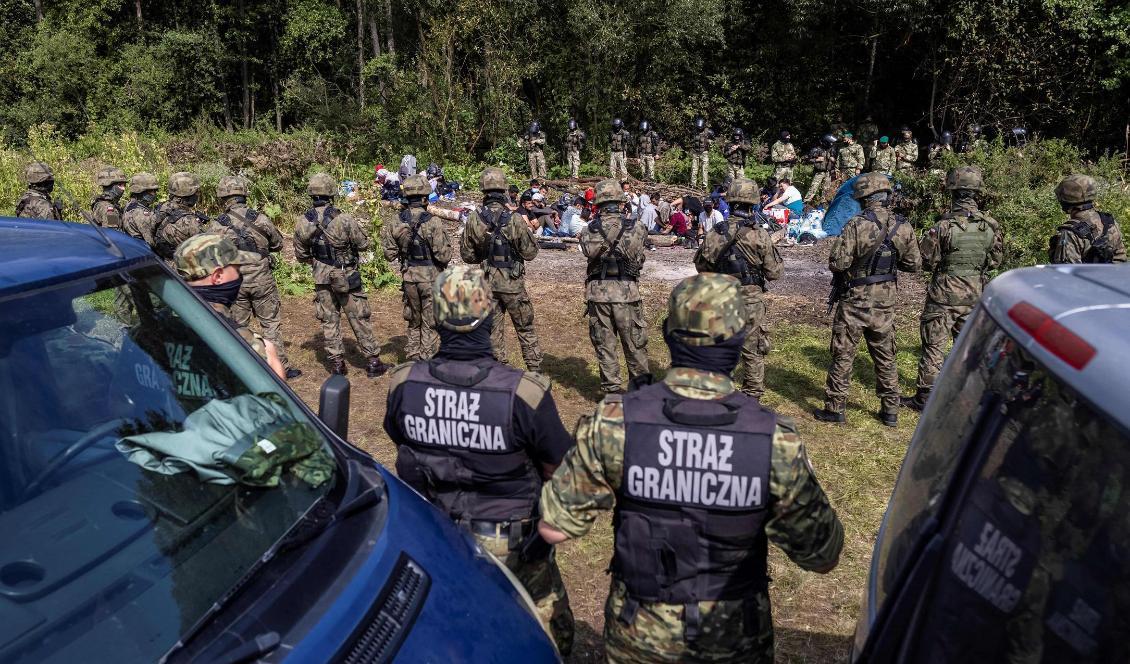 
Polska gränsvakter står bredvid migranter i samhället Usnarz Gorny nära Bialystock i nordöstra Polen vid gränsen mot Belarus den 10 augusti 2021. Foto: Wojtek Radwanski/AFP via Getty Images                                            