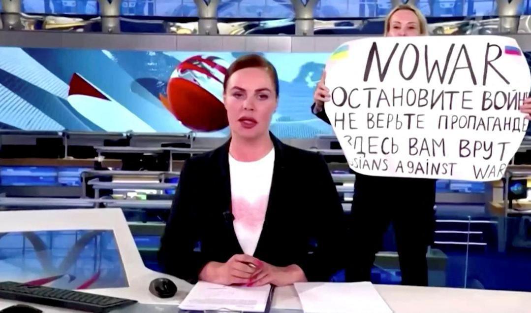 Mitt under en nyhetssändning tog sig en kvinna in i studion och höll upp en skylt med budskapet "Nej till kriget. Tro inte på propagandan. Här ljuger man för er". Foto: Kanal 1/Reuters/TT