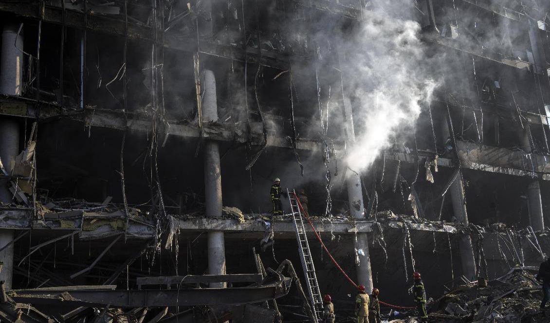 Brandmän försöker att släcka en brand som uppstod efter att ett shoppingcenter i Kiev beskjutits på måndagen. Foto: Rodrigo Abd/AP/TT