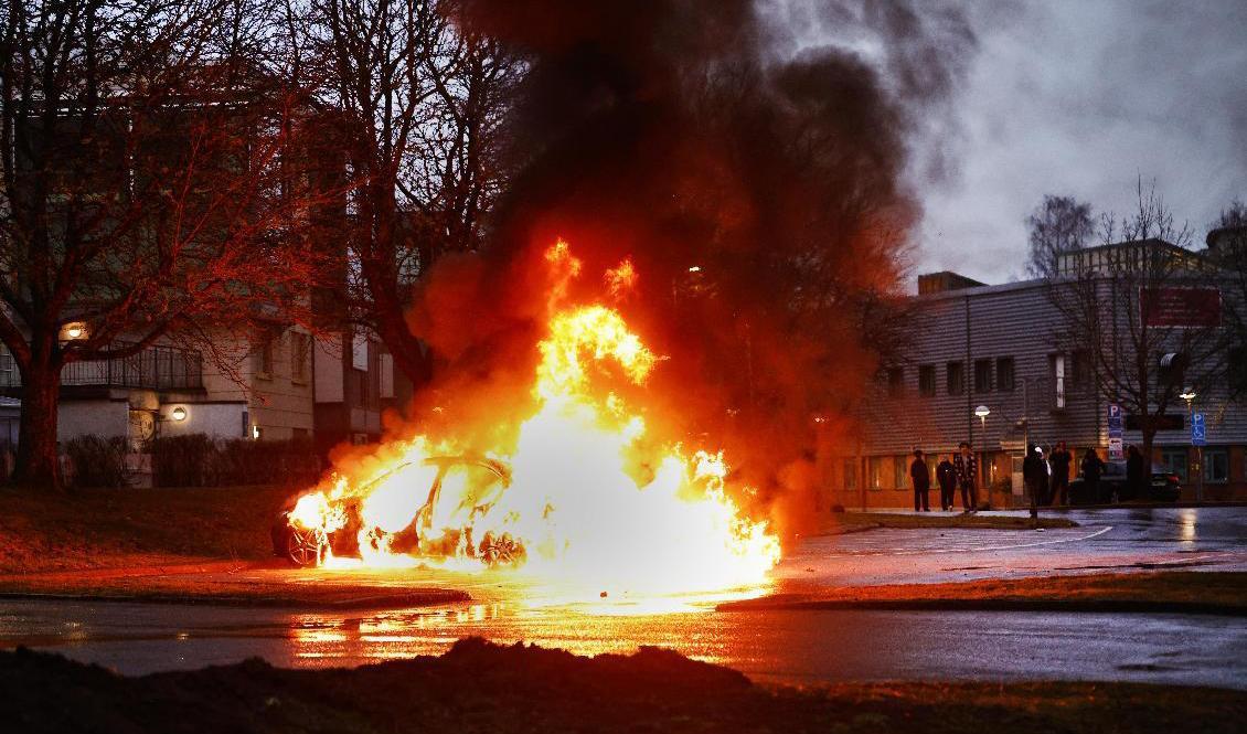 En bil brinner för fullt på en parkering i samband med upplopp i Navestad i Norrköping på torsdagskvällen. Foto: Stefan Jerrevång/TT