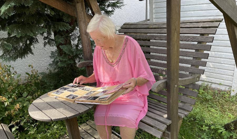 
Eeva Jacobson sitter i sin trädgård i Linköping och tittar på gamla foton från det tidiga 1940-talet, när hon nyligen hade kommit till Sverige. Foto: Göran Jacobson                                            