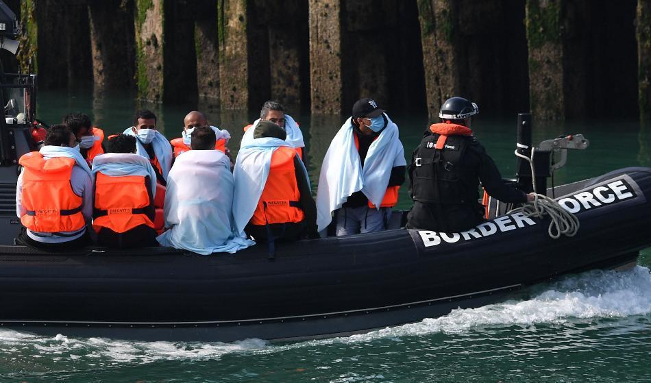 

Den brittiska gränspolisen för över invandrare till en patrullbåt efter att de anträffats i en ribbåt i Engelska kanalen kanalen på väg från Frankrike till Dover den 13 augusti 2020. Foto: Ben Stansall/AFP via Getty Images                                                                                        