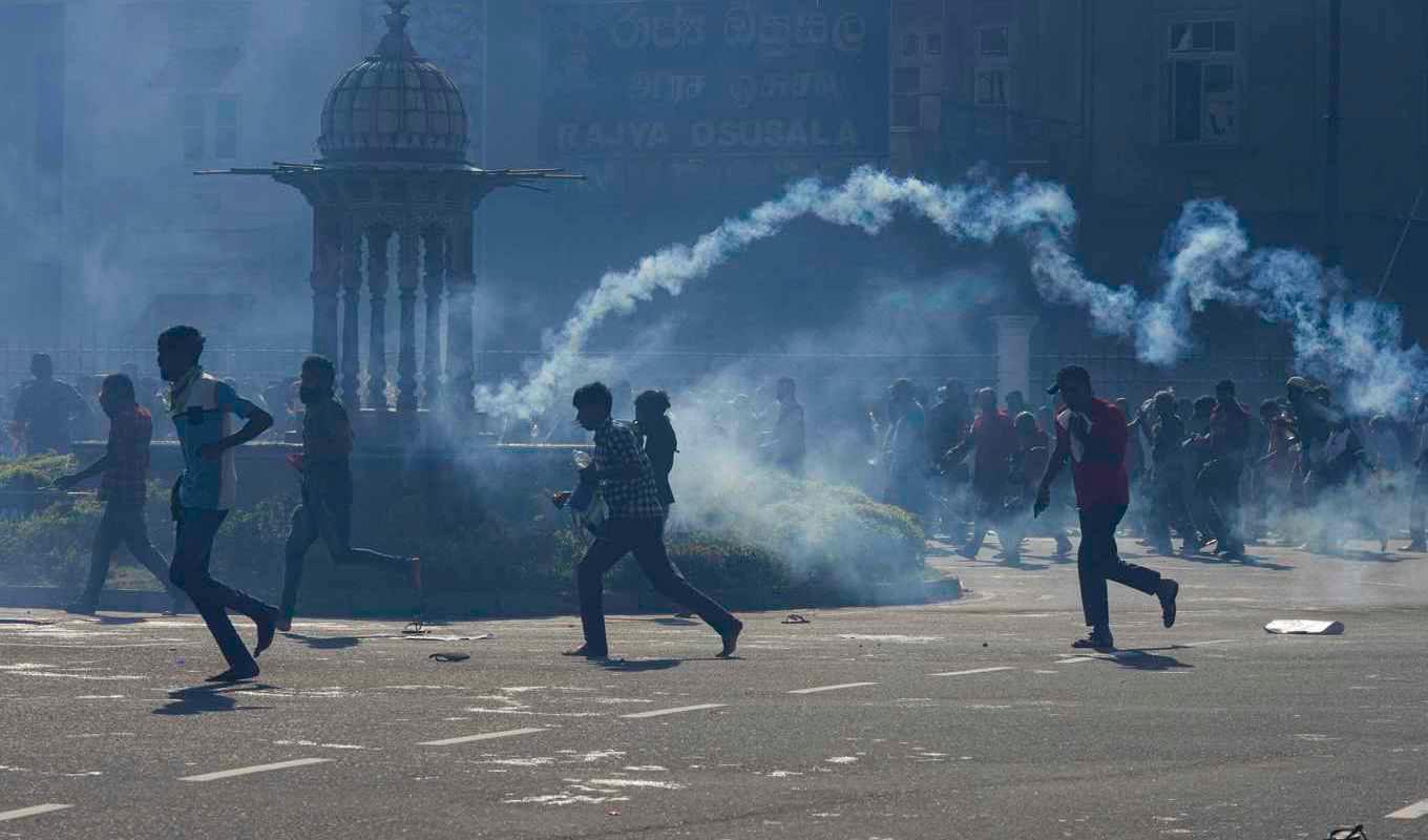 Demonstranter i Colombo flyr polisens tårgas. Foto: Eranga Jayawardena/AP/TT