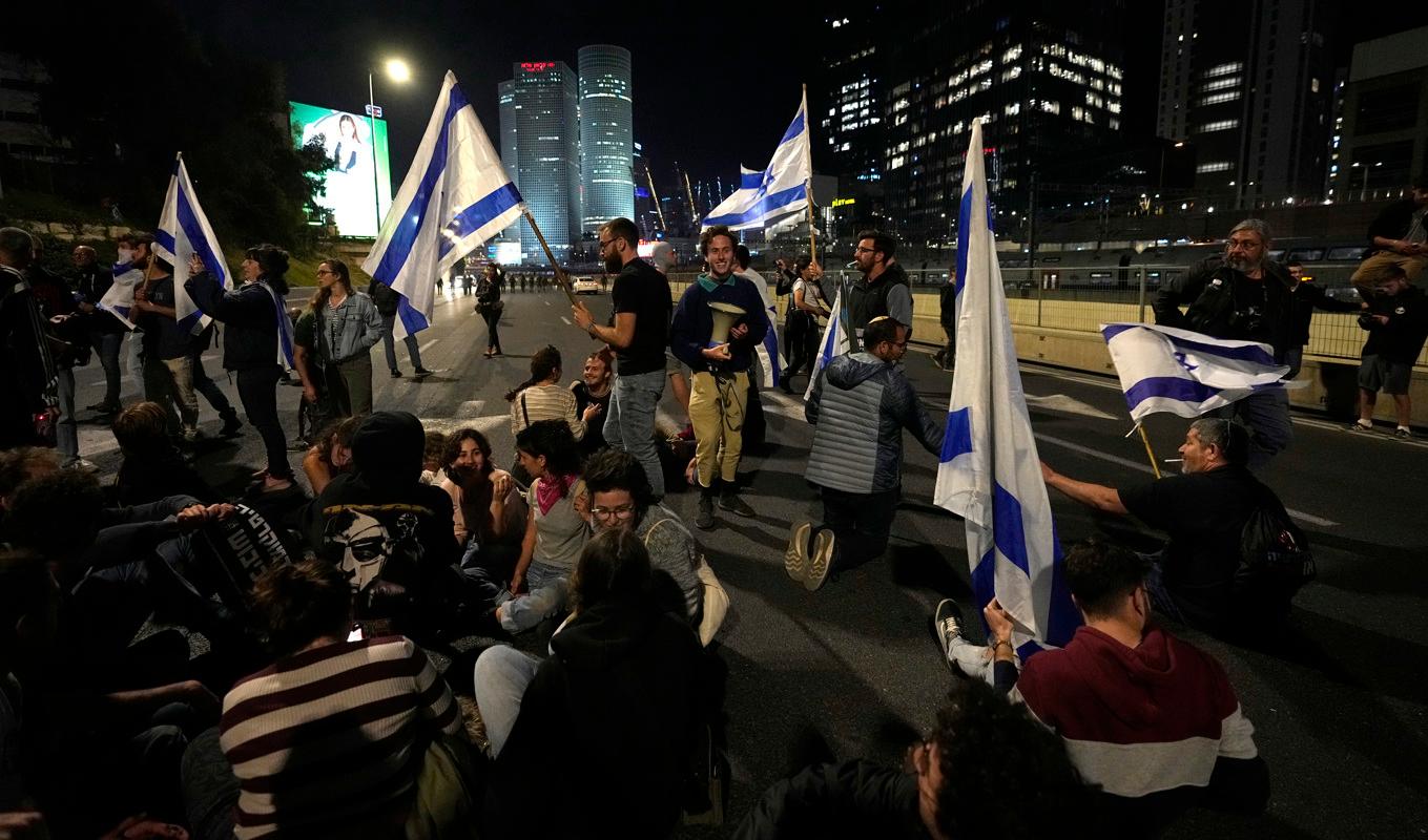 Israeler blockerar en motorväg utanför Tel Aviv i protest mot regeringens förslag att ändra rättsväsendet. Foto: Ohad Zwigenberg/AP/TT