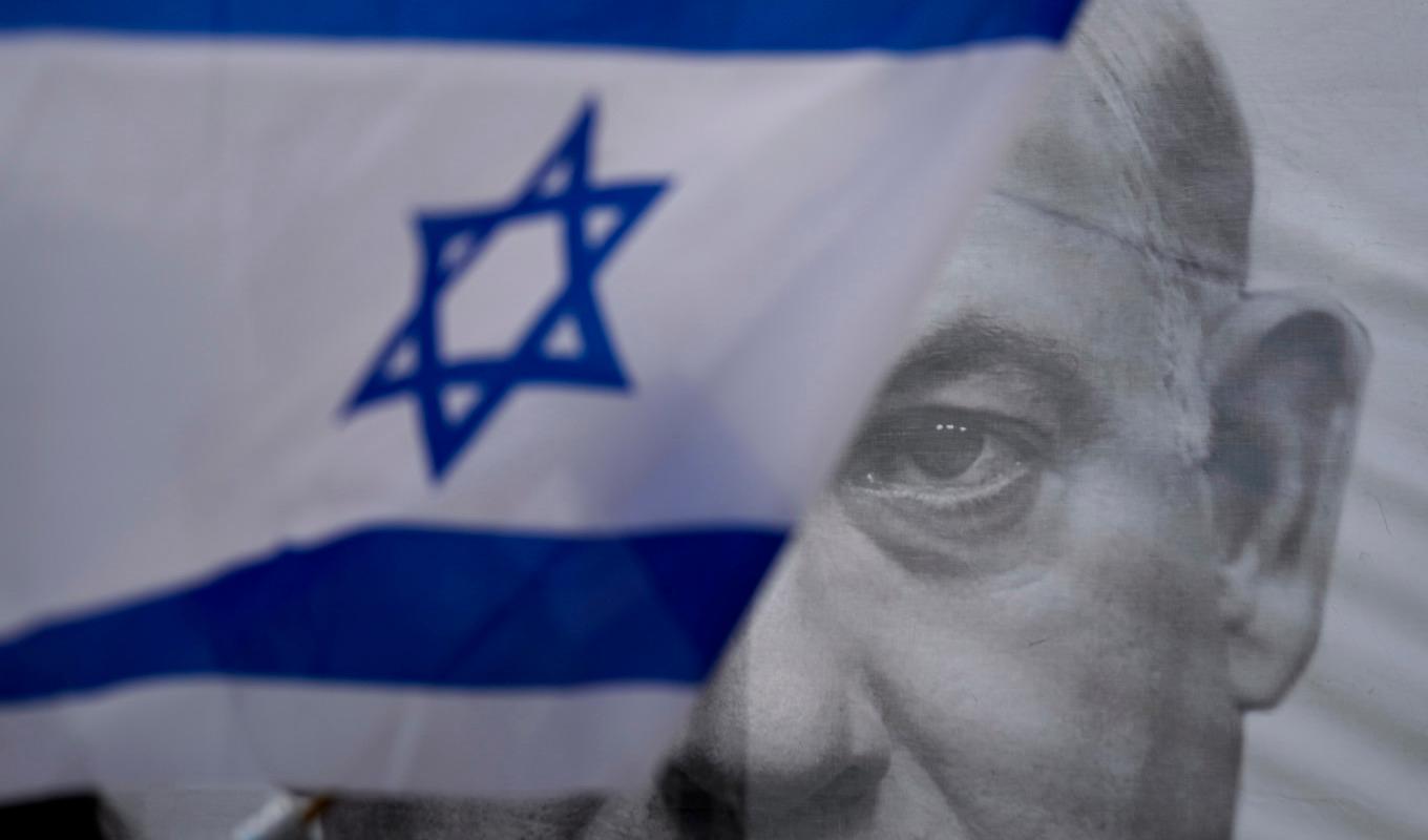Demonstranter höll upp Israels flagga invid en bild på Israels premiärminister Benjamin Netanyahu under helgens stora protester. Foto: Ariel Schalit/AP/TT
