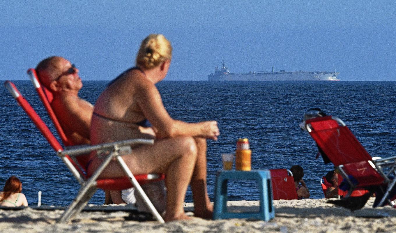 Människor kopplar av på stranden i Rio de Janeiro den 27 februari, medan det iranska militärfartyget IRIS Makran seglar i havet utanför. Foto: Carl de Souza/AFP via Getty Images