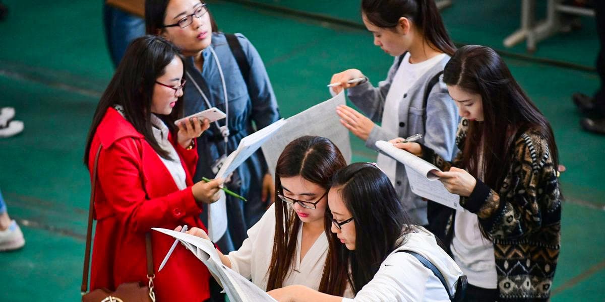 Unga vuxna läser platsannonser under en jobbmässa på Shenyang Aerospace University i Shenyang, Liaoning provinsen, den 13 maj 2017. Foto: STR/AFP via Getty Images