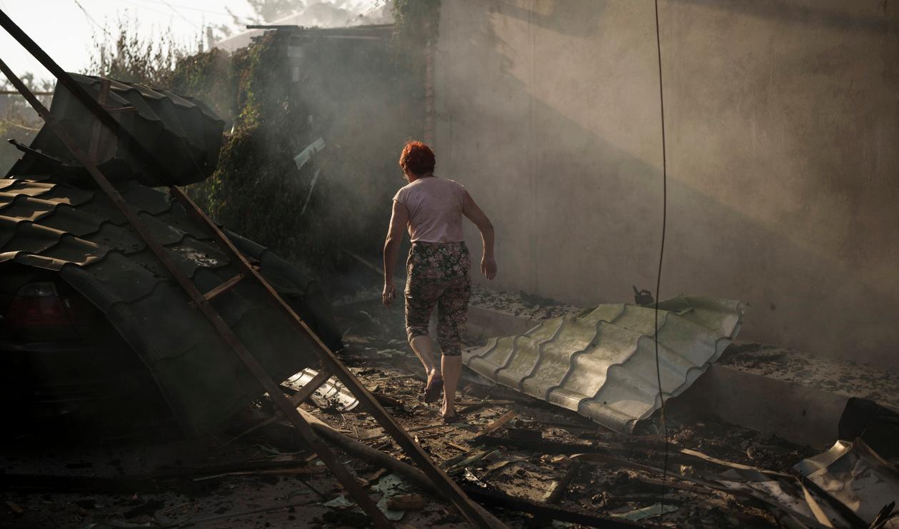 En kvinna utanför sitt sönderbombade hus tidigare i sommar i Cherson. Foto: Felipe Dana/AP/TT