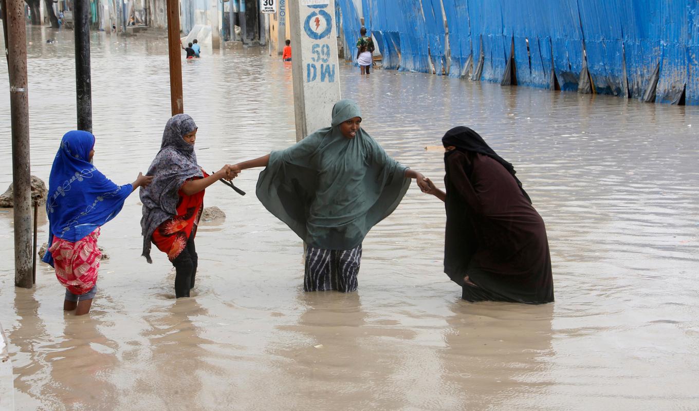 Kvinnor vadar över en översvämmad gata i Somalias huvudstad Mogadishu på måndagen. Foto: Farah Abdi Warsameh/AP/TT