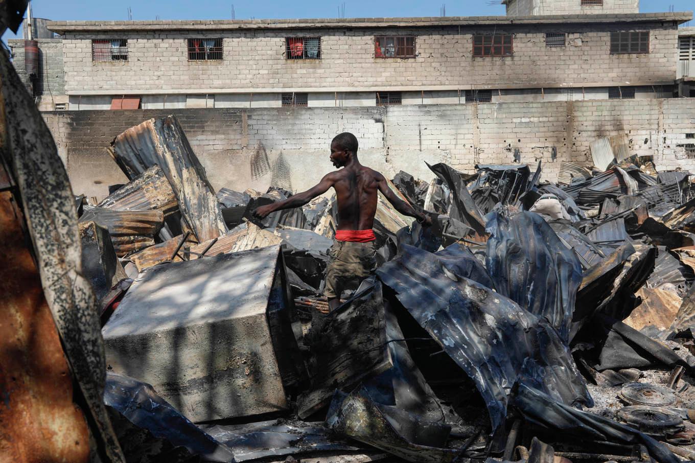 En man går igenom en nedbrunnen bilverkstad i Haitis huvudstad Port-au-Prince. Foto: Odelyn Joseph/AP/TT