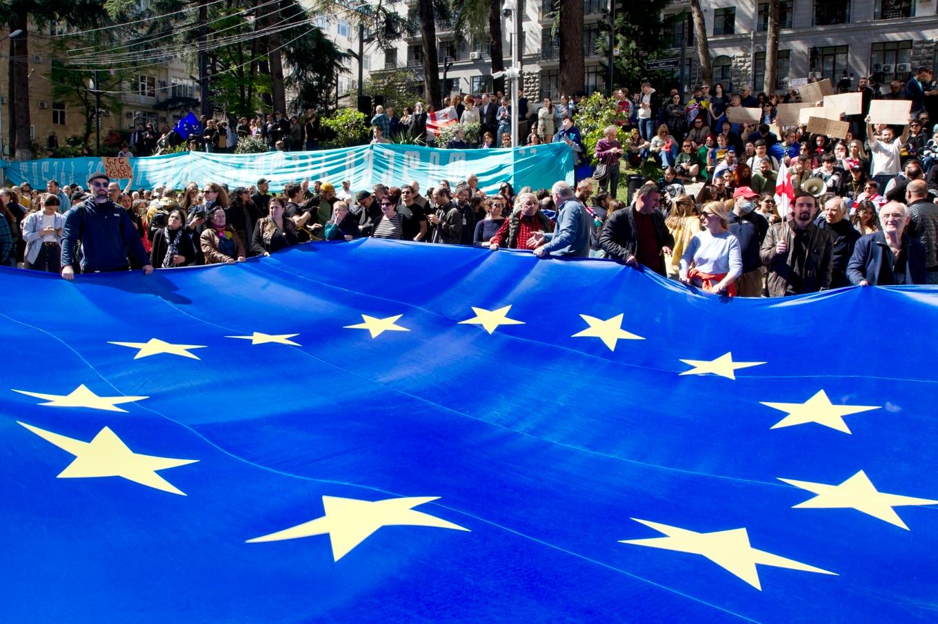 Demonstranter har vecklat upp en stor EU-flagga utanför parlamentsbyggnaden i Tbilisi på måndagen. Foto: Shakh Aivazov/AP/TT