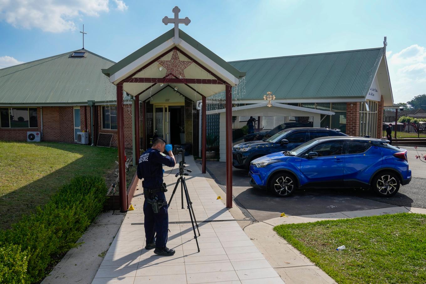 En polis framför kyrkan i Wakely i Sydneys utkanter, där knivhuggningen skedde. Foto: Mark Baker/AP/TT