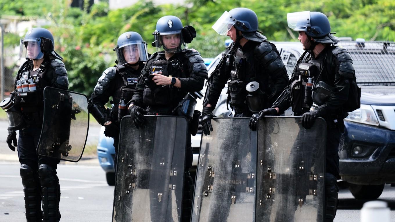 Franska poliser med sköldar står vid ingången till Vallée-du-Tir-distriktet i Nouméa i Nya Kaledonien den 14 maj. Foto: Theo Rouby/AFP via Getty Images