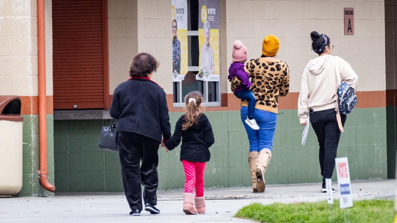 Vuxna och barn på väg in i en vallokal i Orange, Kalifornien den 5 mars. Allt fler mammor syns och hörs i den politiska debatten i USA. Foto: John Fredricks
