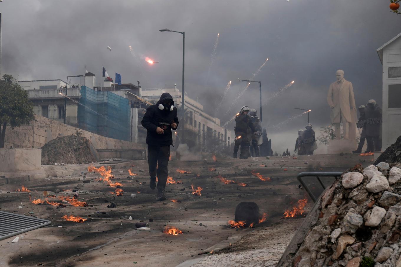 En demonstrant i förödelsen efter sammanstötningar nära parlamentet i centrala Aten på fredagen. Foto: Petros Giannakouris/AP/TT