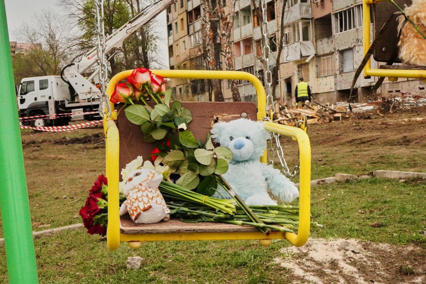 Leksaker och blommor har lämnats på en gunga för att hedra offren på platsen för fredagens ryska attack i Kryvyj Rih i Ukraina. Foto: AP/TT
