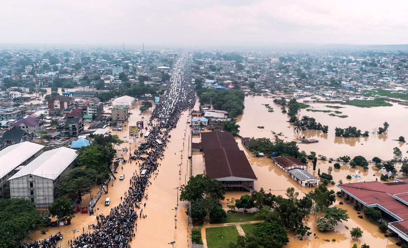 Människor vadar genom de översvämmade vägarna i huvudstaden Kinshasa. Foto: Samy Ntumba Shambuyi/AP/TT