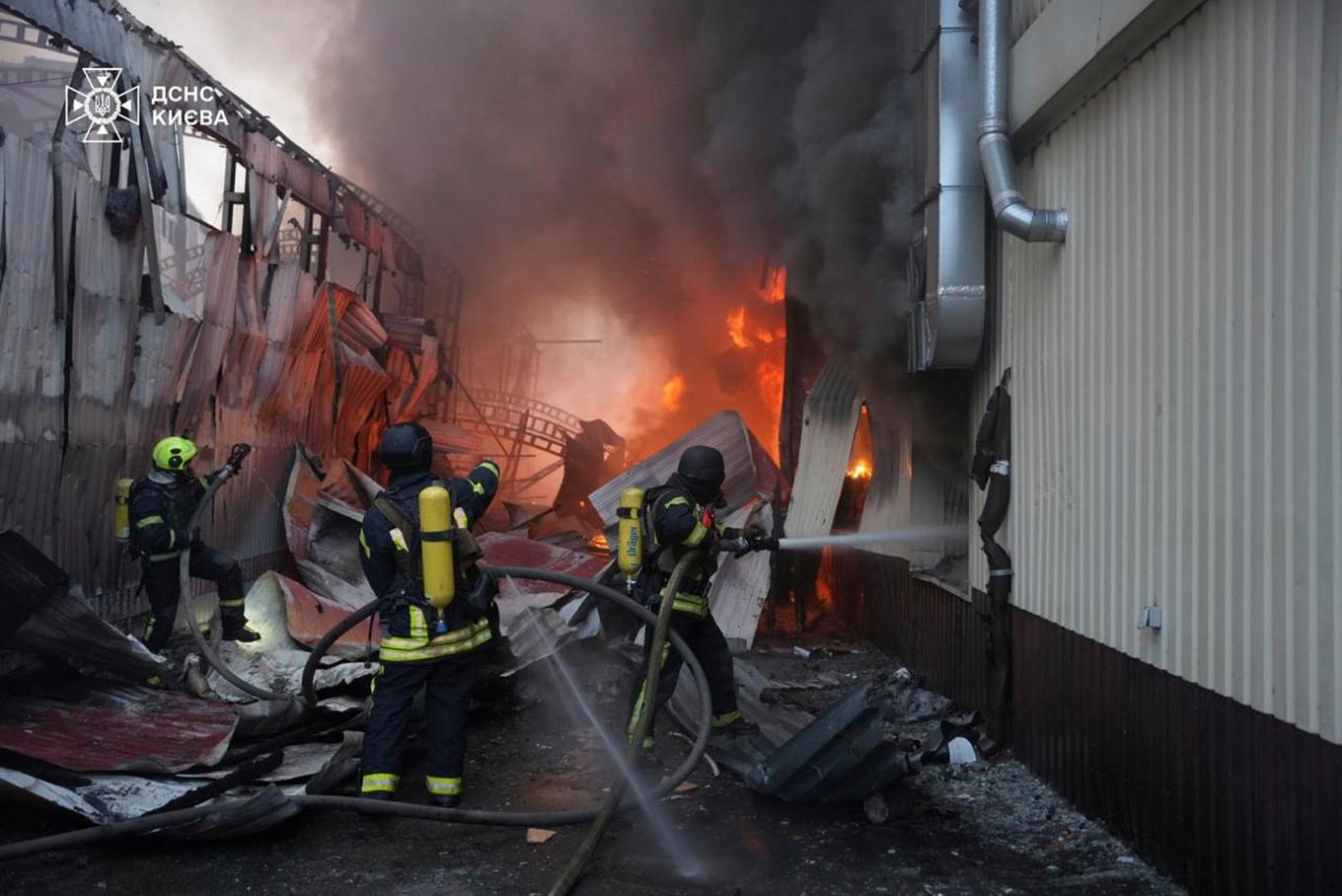 Räddningsarbetare släcker en brand som uppstått till följd av en rysk robotattack mot Kiev under söndagen. Foto: Ukrainas räddningstjänst via AP/TT