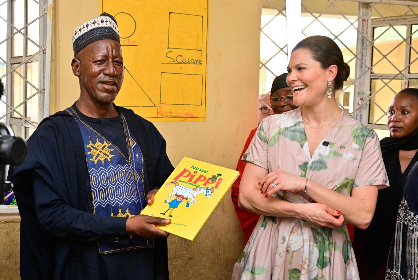 Kronprinsessan Victoria överlämnar boken "Känner du Pippi Långstrump?", översatt till nigeriansk pidgin, till rektorn Umar Muhammed Makusidi på LEA-förskolan i Jabi. Foto: Jonas Ekströmer/TT