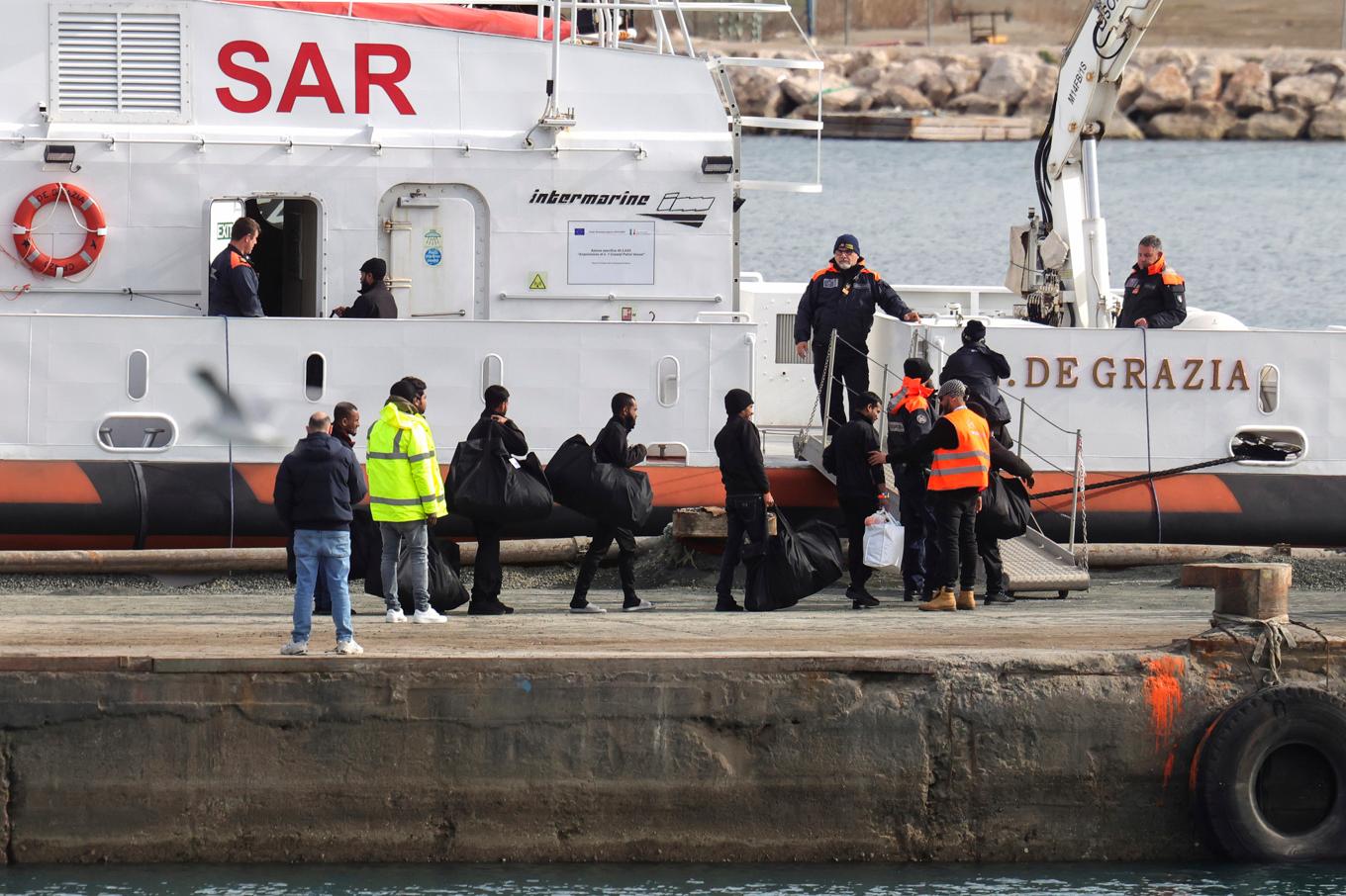 Migranter går ombord på ett fartyg tillhörande Italiens kustbevakning i början av februari. Den gången stoppades utvisningarna av en italiensk domstol. Foto: Vlasov Sulaj/AP/TT