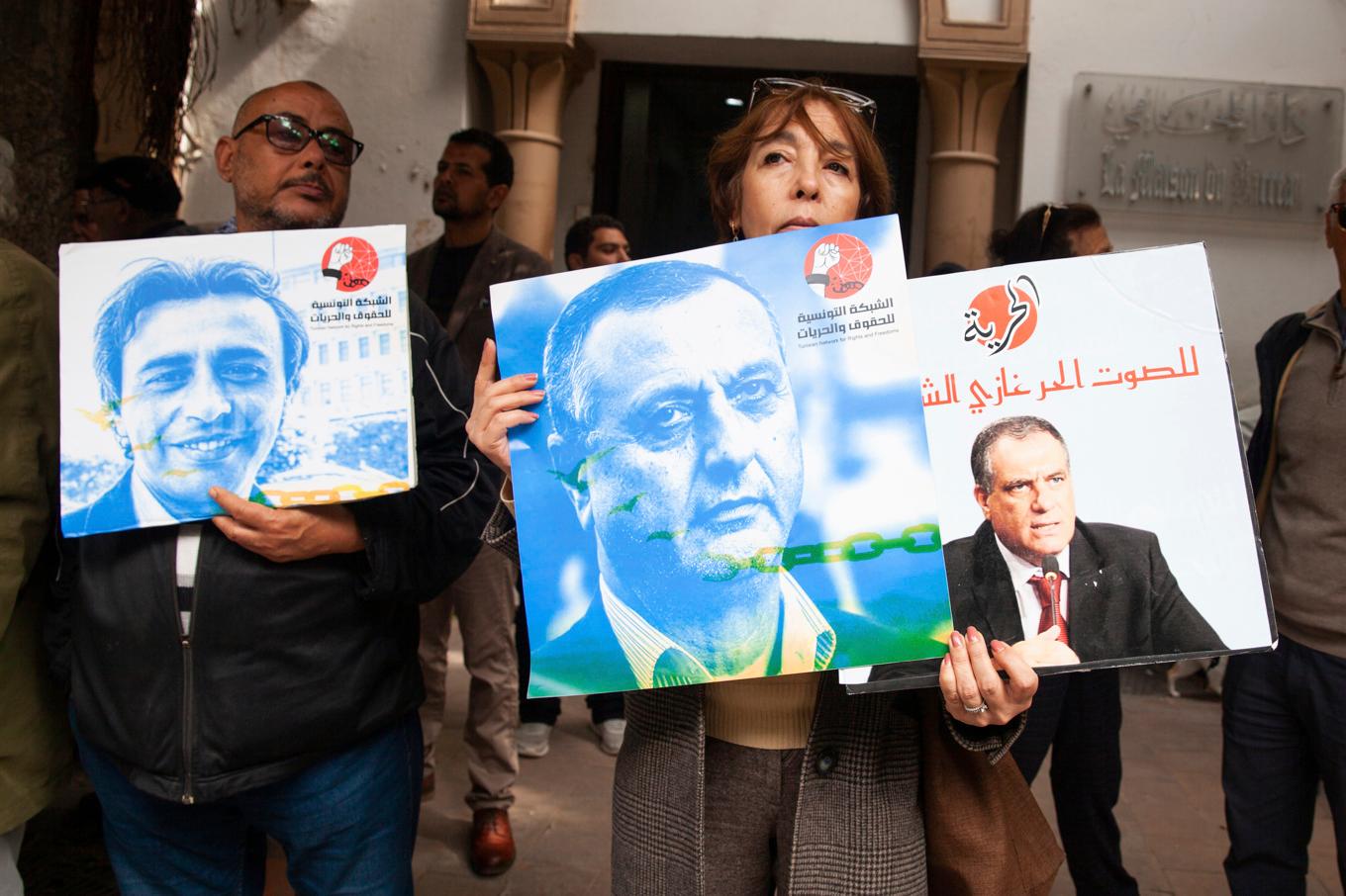 Demonstranter håller upp bilder på de åtalade utanför domstolen i Tunis. Bild från i mars. Foto: Ons Abid/AP/TT