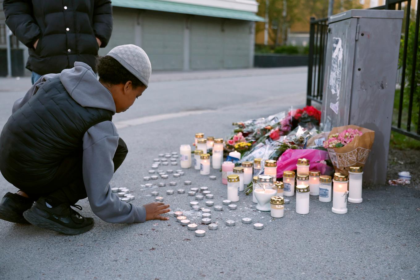 En minnesplats där människor lämnat blommor och ljus dagen efter att tre personer dödats i en skottlossning i en frisörsalong i Uppsala. Foto: Fredrik Persson/TT