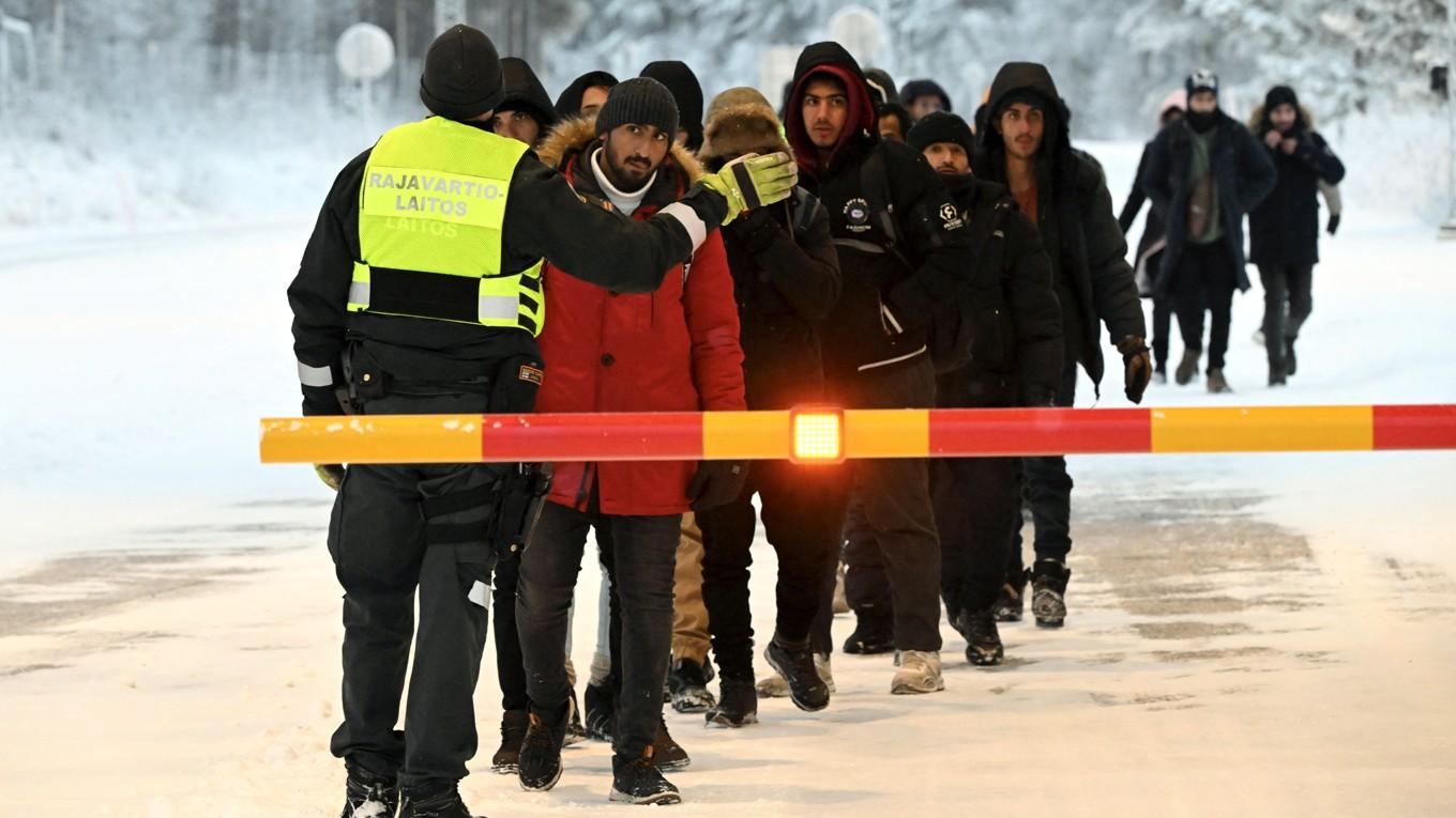 En finsk gränsvakt talar med migranter vid den internationella gränsövergången i Salla i norra Finland den 23 november 2023. Foto: Jussi Nukari/Lehtikuva/AFP via Getty Images
