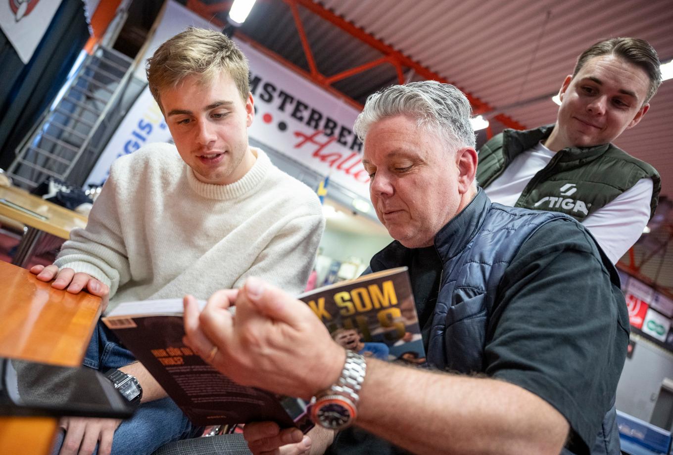 Bordtennisstjärnan Truls Möregårdh kikar i sin bok "Tänk som Truls" tillsammans med pappa Carl och storebroder Malte Möregårdh. Foto: Johan Nilsson / TT