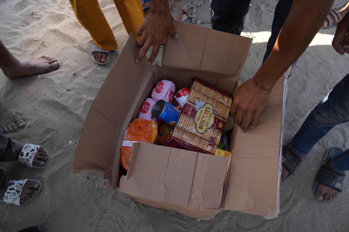 Några palestinier i Gaza öppnar en av de matlådor som distribuerats via den kontroversiella organisationen GHF. Foto: Abdel Kareem Hana/AP/TT