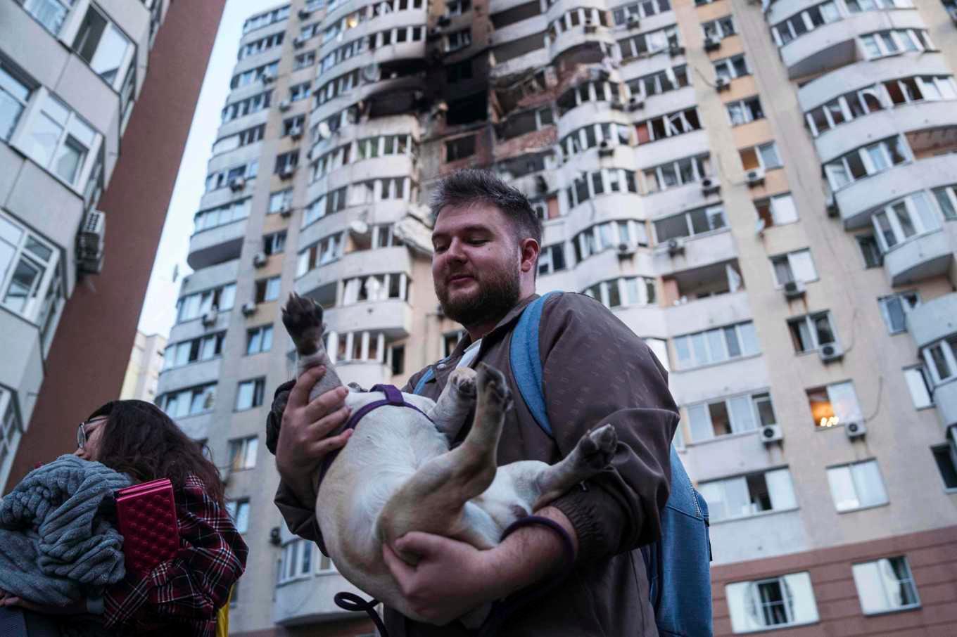 En man och hans hund flyr från ett skadat flervåningshus i Kiev på fredagen. Foto: Evgeniy Maloletka/AP/TT