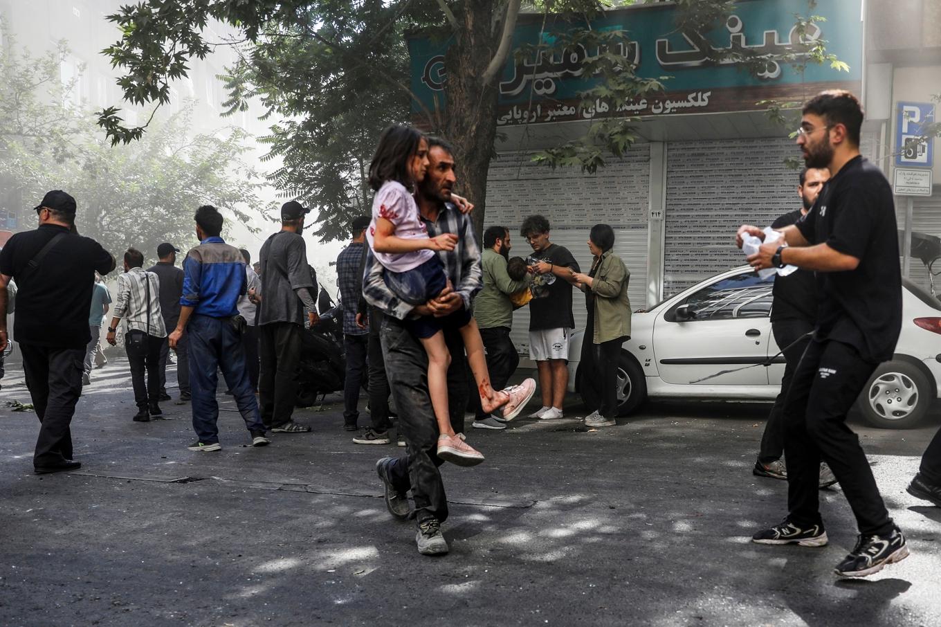 En man bär ett barn som skadats i en explosion i Teheran under söndagen. Foto: Morteza Zangene/ISNA via AP/TT