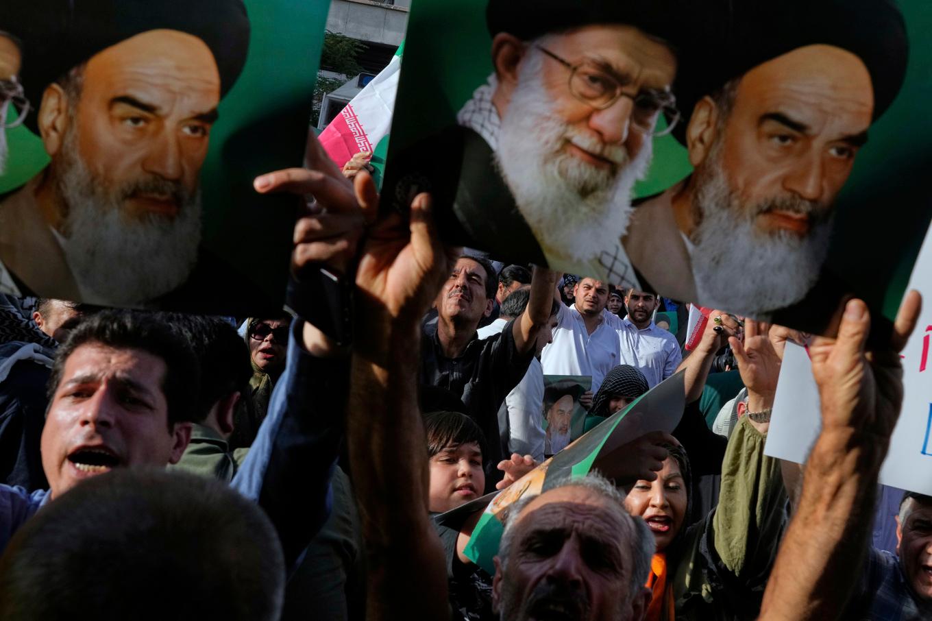 Bilder av Irans högste ledare ayatolla Khamenei och hans företrädare ayatolla Khomeini hålls upp vid en protest i Teheran under söndagen mot västvärldens Iranpolitik. Foto: Vahid Salemi/AP/TT