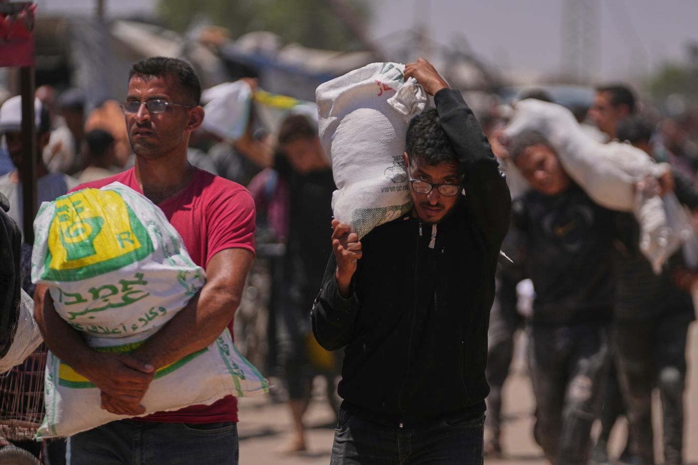 Palestinier bär mat och annan humanitär hjälp som levererats av Gaza Humanitarian Foundation (GHF), i Rafah i södra Gaza tidigare i veckan. Foto: Abdel Kareem Hana/AP/TT