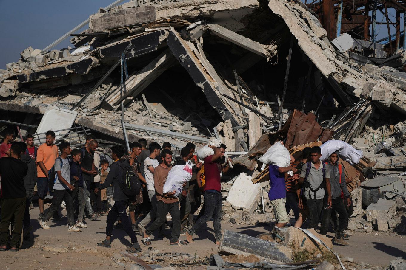 Palestinier bär säckar med nödhjälp vid ett av GHF:s hjälpcenter i Gaza under torsdagen. Foto: Abdel Kareem Hana/AP/TT